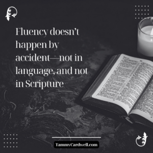 Open Bible on a dark table with the quote “Fluency doesn’t happen by accident—not in language, and not in Scripture.”